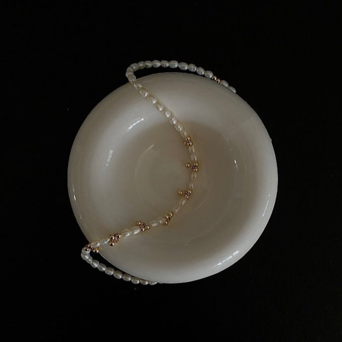 Showcasing the Livia Beaded Necklace crafted from natural freshwater pearl and sprinkled with 14k gold-plated beads.
