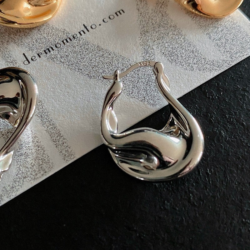 Crafted from white rhodium-plated silver, the Astrid Curve Hoop Earrings feature a unique and eye-catching design, adding a touch of modern elegance to your everyday style.