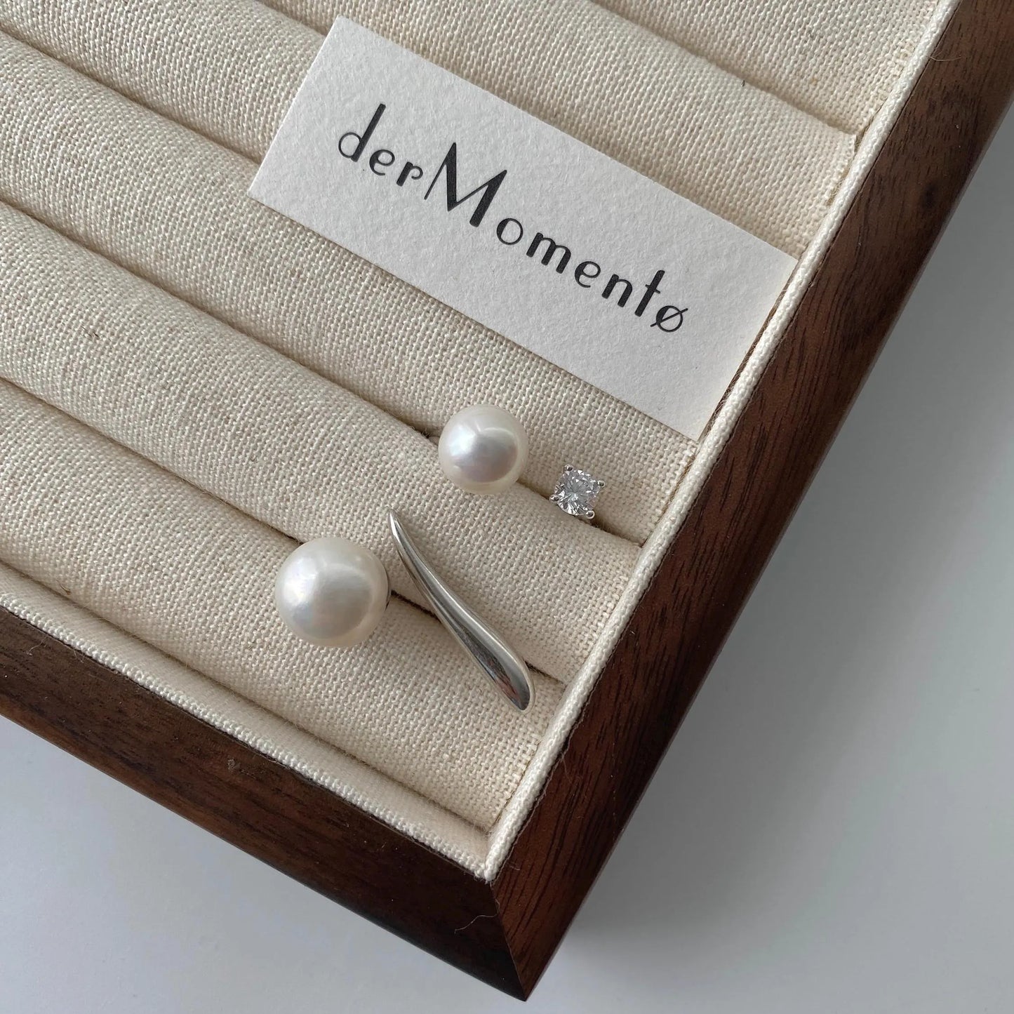 derMomentø - Handcrafted large pearl open ring with a naturally grown freshwater baroque pearl, set on a white rhodium-plated silver band. Displayed with another pearl open ring a ring tray with branding name derMomentø.