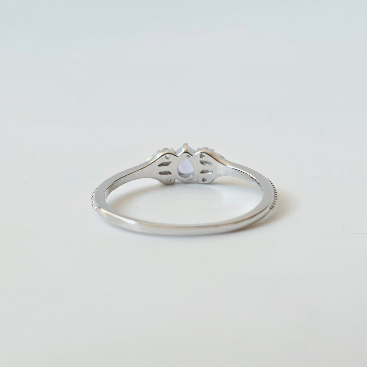 Detail of pear-shaped tanzanite and milgrain-style silver ring setting from back side