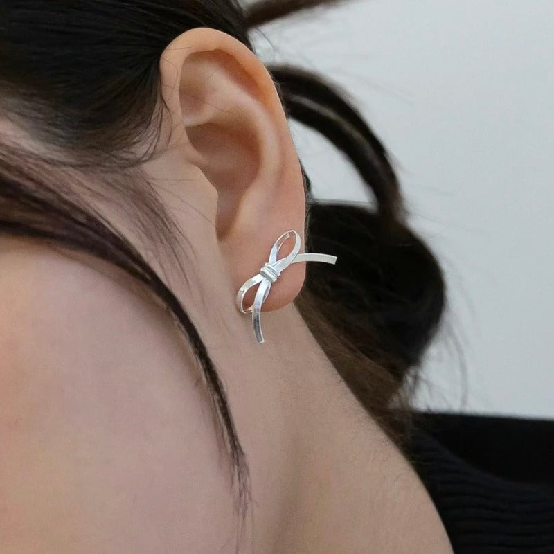Model wearing the Amelia Ribbon Stud Earrings - Bow-tie shaped stud earrings crafted from sterling silver flat snake chain material.