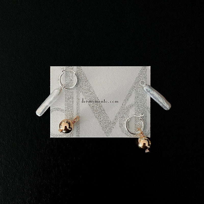 The Golden Ball & Pearl Charm Hoop Earrings feature a drop baroque pearl and a 14KGF golden ball charm suspended from mini sterling silver hoops. These versatile hoops can be worn solo or with any drop and charm to suit your style.