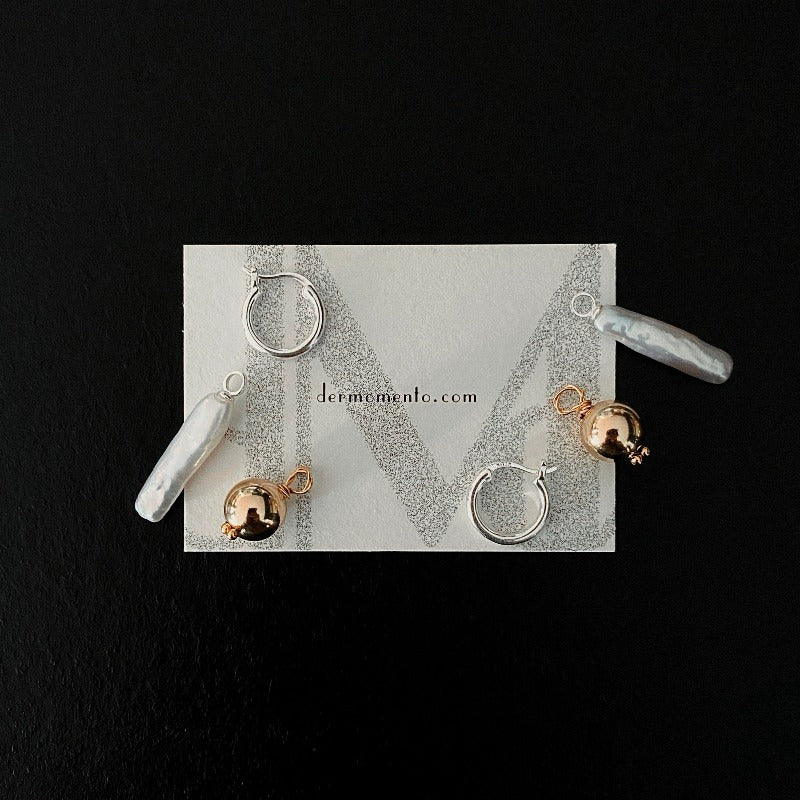 The Golden Ball & Pearl Charm Hoop Earrings feature a drop baroque pearl and a 14KGF golden ball charm suspended from mini sterling silver hoops. These versatile hoops can be worn solo or with any drop and charm to suit your style.
