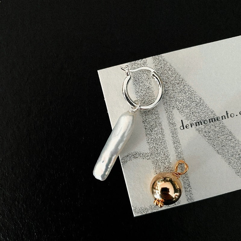 The Golden Ball & Pearl Charm Hoop Earrings feature a drop baroque pearl and a 14KGF golden ball charm suspended from mini sterling silver hoops. These versatile hoops can be worn solo or with any drop and charm to suit your style.