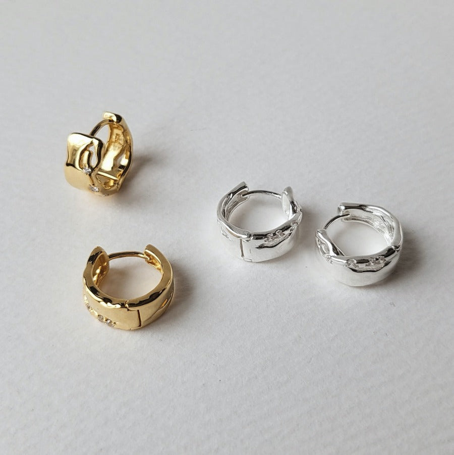 Two pairs of Elfi Hoop Earrings crafted from 18K gold vermeil and silver, feature a unique texture with uneven cutouts and small cubic zirconia embellishments.
