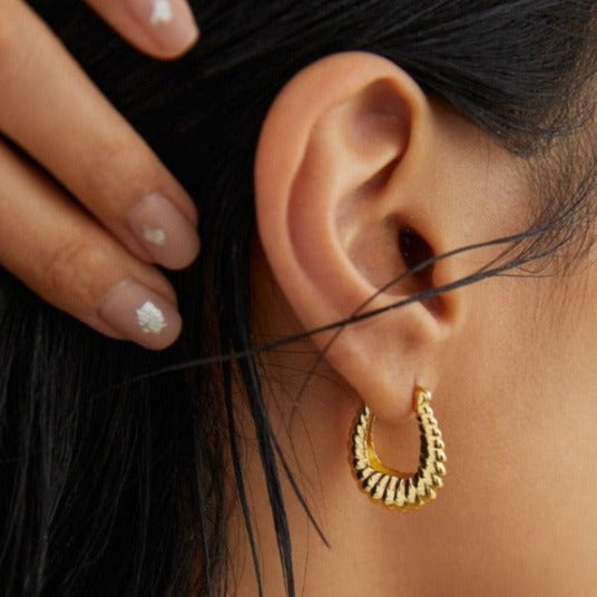 Model wearing the twist bold hoop earrings.