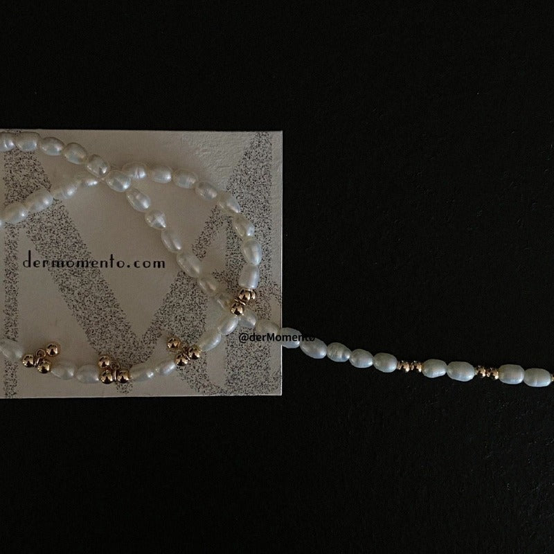 Showcasing the Livia Beaded Necklace crafted from natural freshwater pearl and sprinkled with 14k gold-plated beads. With dermomento.com at background.