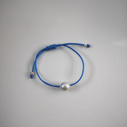 Handmade single pearl silk cord string bracelets featuring a single natural baroque oval pearl with a stunning silver-blue lustre , delicately strung on adjustable blue silk cord and adorned with silver beads.