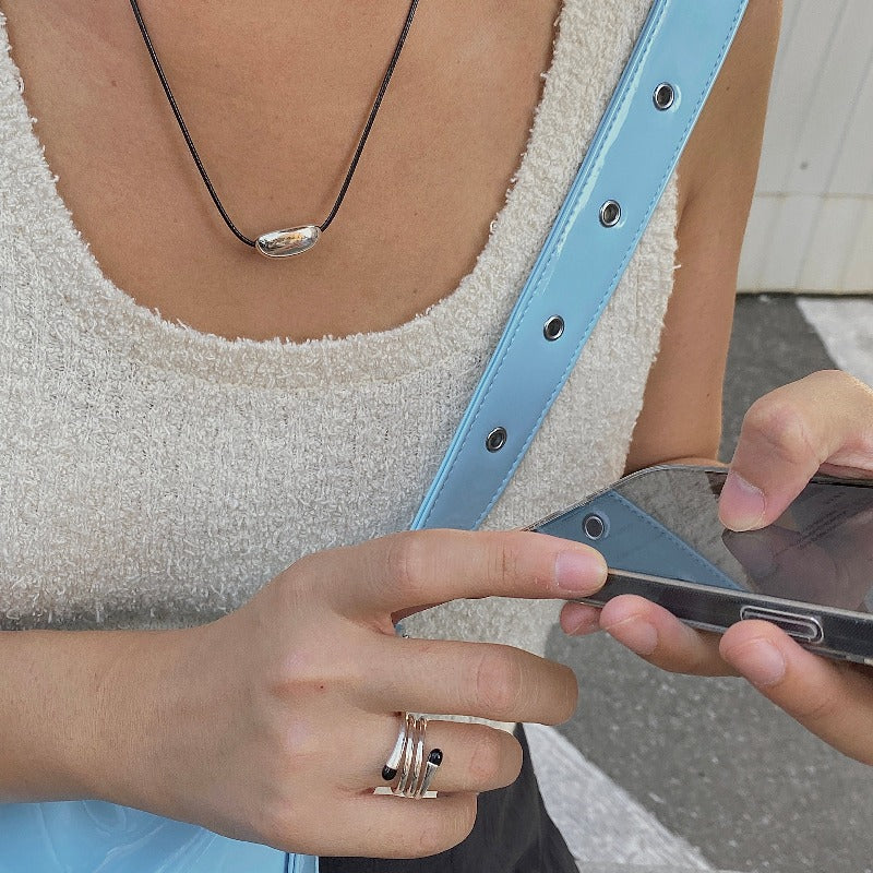 derMomentø - model wearing the minimalist black string cord necklace with silver bean pendant, made with a black leather string cord and featuring a bold chunky bean pendant in sterling silver.