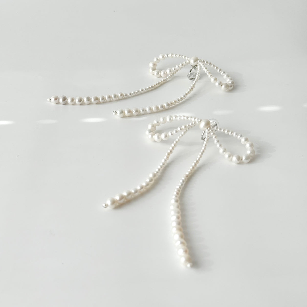 Graduated freshwater pearls forming oversized bow-shaped loops