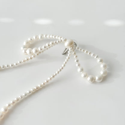 Close-up of silver-tone clip-on fastening on handmade pearl bow earrings