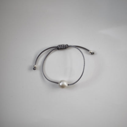 Handmade single pearl silk cord string bracelets featuring a single natural baroque oval pearl with a stunning silver-blue lustre , delicately strung on adjustable gray silk cord and adorned with silver beads.