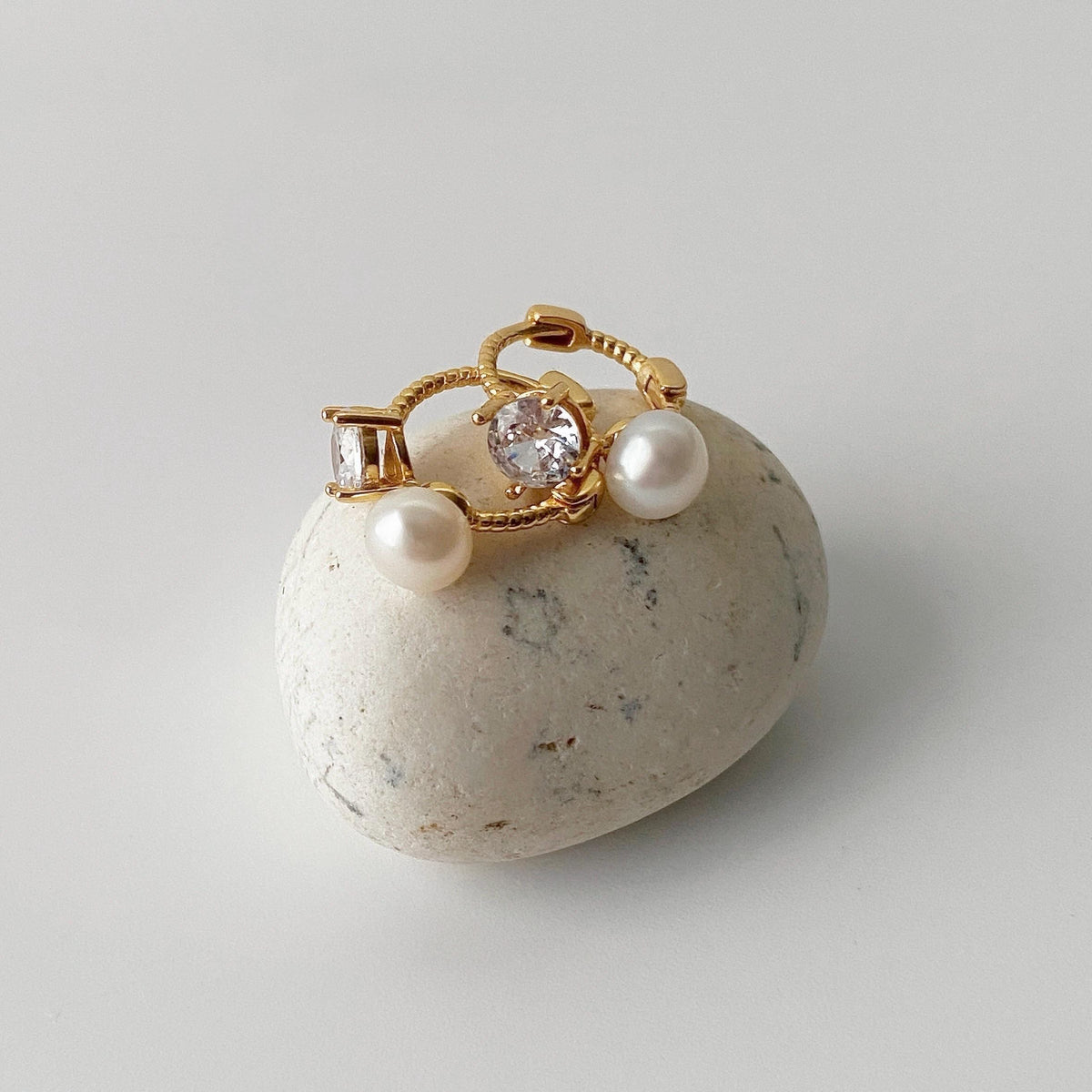 Close-up of freshwater pearl and clear zirconia on gold hoop earring