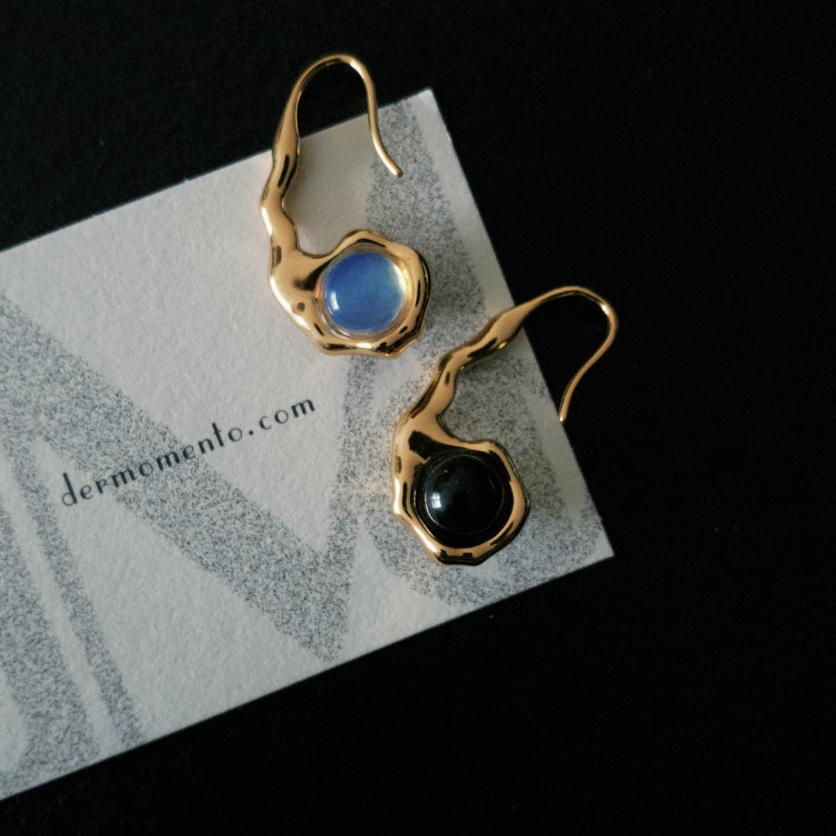 Close-up of HELENA earrings with rounded black onyx and blue opal settings