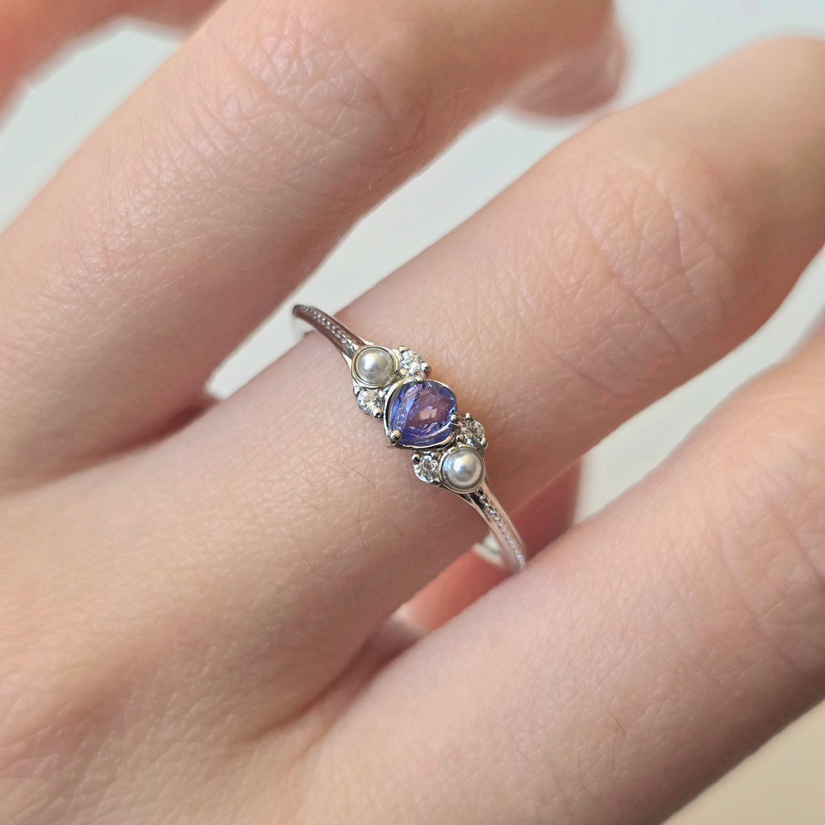 LINNIE sterling silver tanzanite ring worn on hand with shell pearls and cubic zirconia