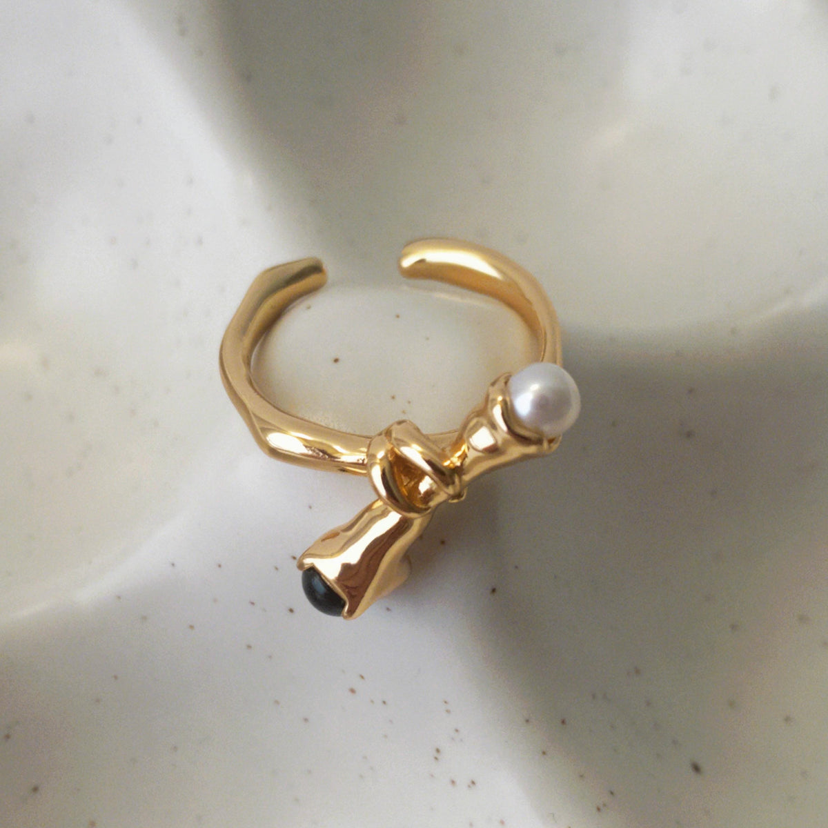 Adjustable pearl and black onyx ring with overlapping knotted band