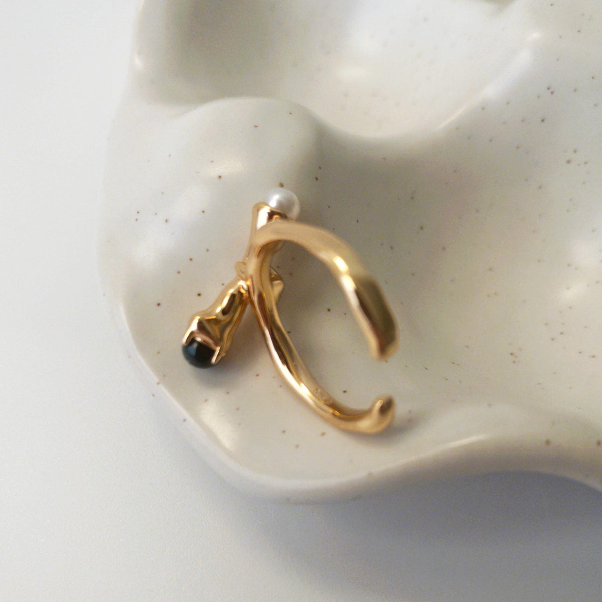 Close-up of sculptural open ring with intertwined metal curves