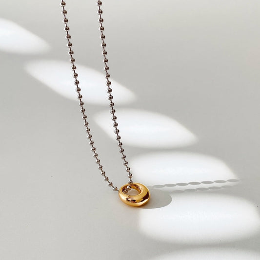  The two-tone hoop pendant choker necklace features a sterling silver bead chain with white rhodium plating and an 18-karat gold vermeil hoop doughnut/ring form pendant. 