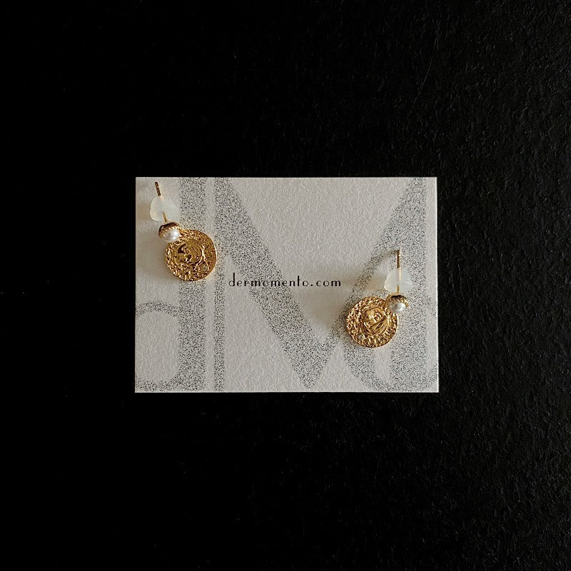 The Alwina Drop Stud Earrings - a mini pearl design (non-natural pearl) expertly enveloped in 18K gold vermeil silver and accented by tiny zircons and intricate tin relief detailing on each round tile. With dermomento.com at background.