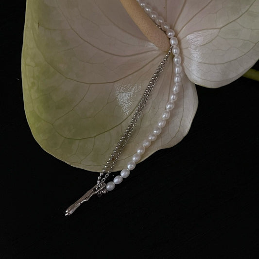 Half silver chain half pearls-sided necklace with a removable curved pendant, crafted in rhodium-plated silver. A perfect blend of modern and classic styles.