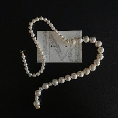 The Mira Crystal Pearl Necklace combines crystal pearls in a delightful gradient arrangement, accented with a golden magnetic clasp. Brand website "dermomento.com" at background.