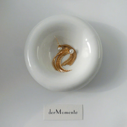 THEA gold vermeil pearl tassel earrings arranged on a white ceramic dish