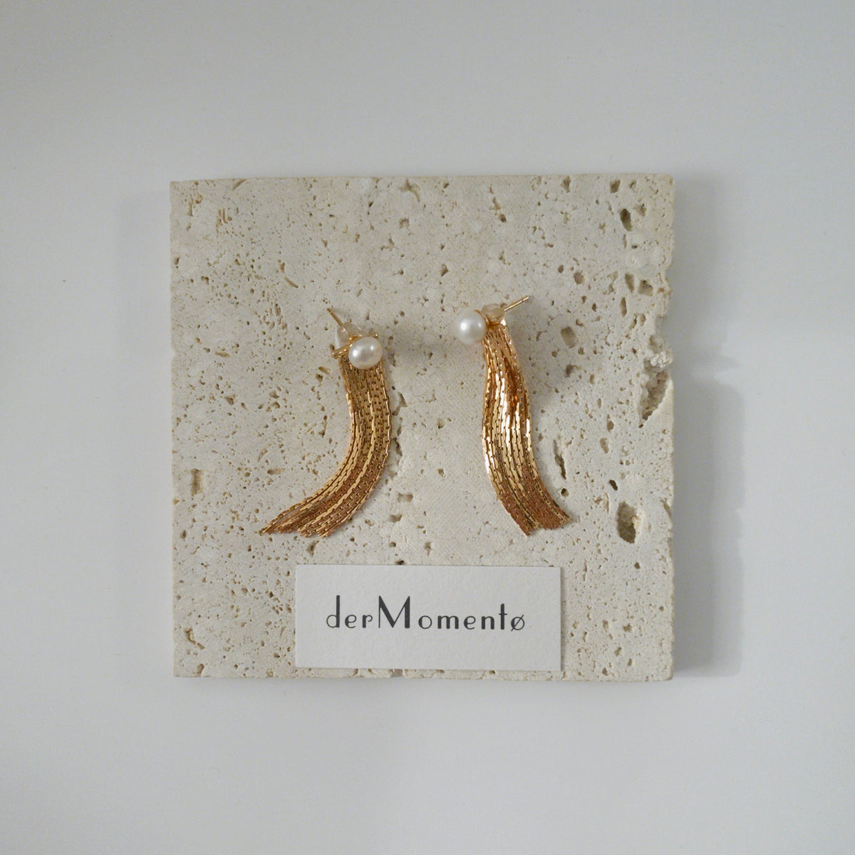 THEA freshwater pearl and gold chain tassel earrings displayed on stone