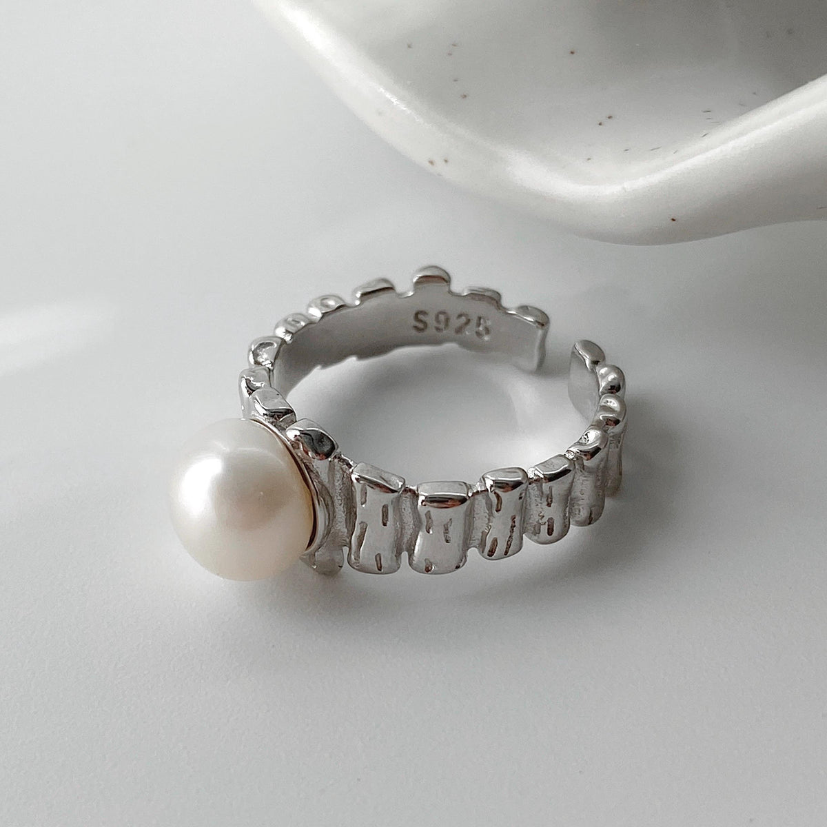 Close-up of irregular textured silver surface and freshwater pearl