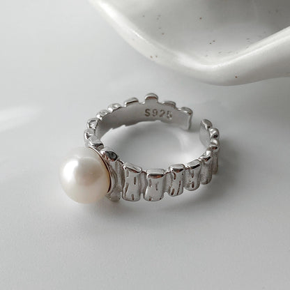 Close-up of irregular textured silver surface and freshwater pearl