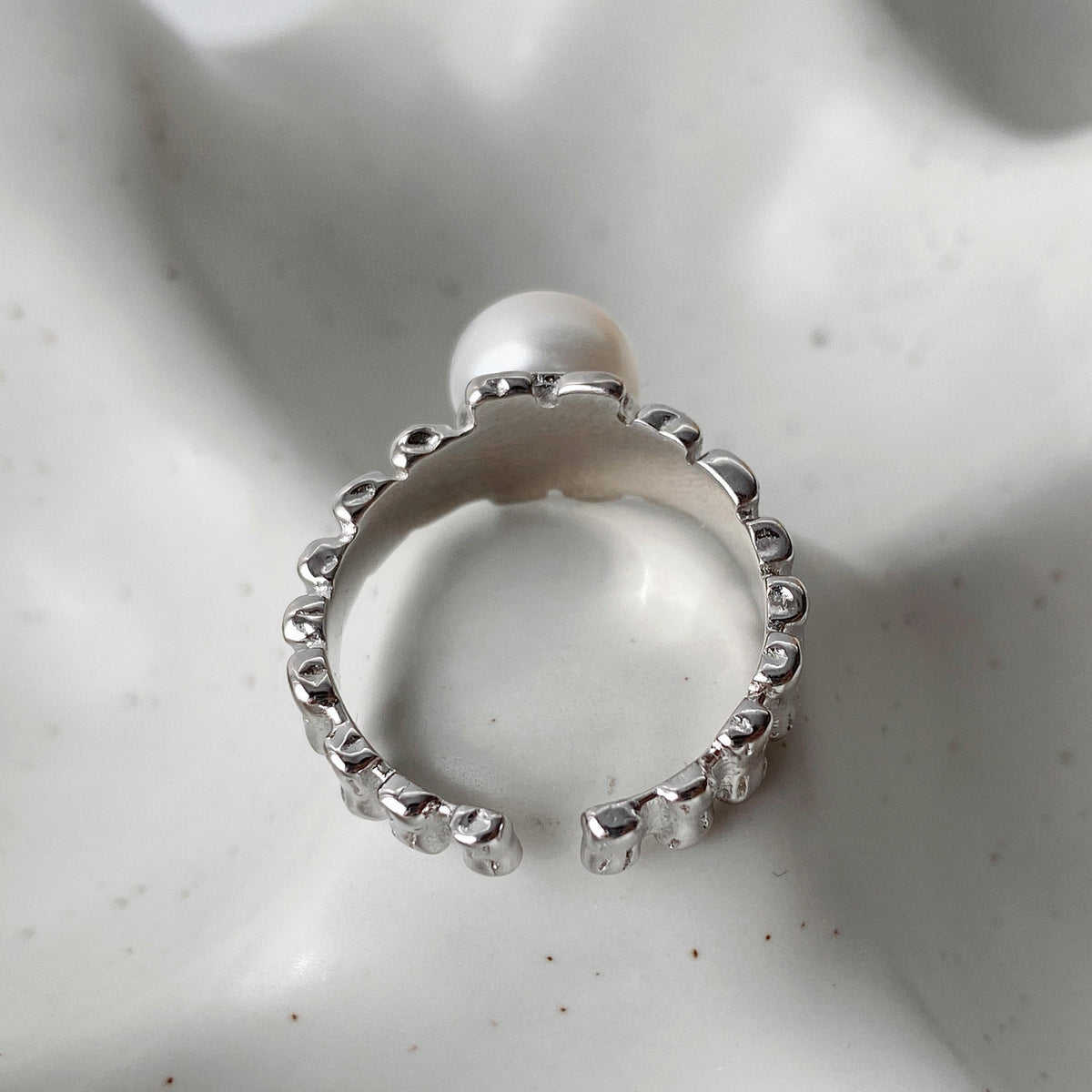 Close-up of the inside part of irregular textured silver surface and freshwater pearl