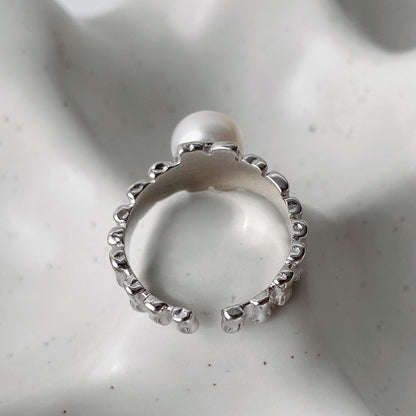 Close-up of the inside part of irregular textured silver surface and freshwater pearl