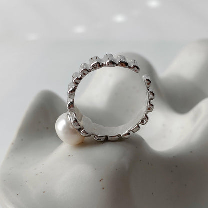 Close-up of the side view of irregular textured silver surface and freshwater pearl